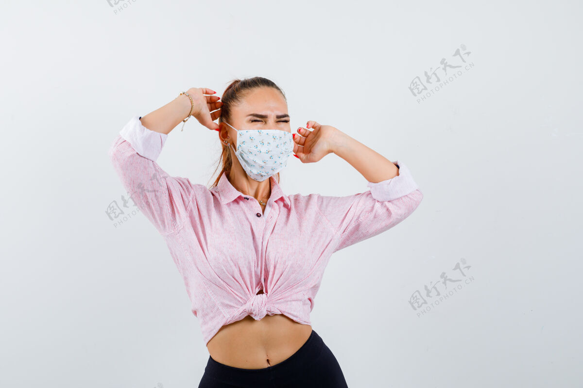 平静年轻女士穿着衬衫 戴着面具 舒展着上身 看起来很放松前视图上面舒适室内