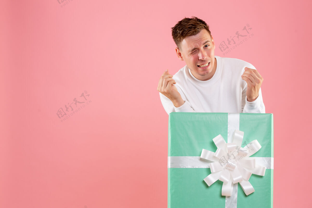 粉色正面图年轻的男性在一个粉红色的背景内呈现圣诞正面微笑