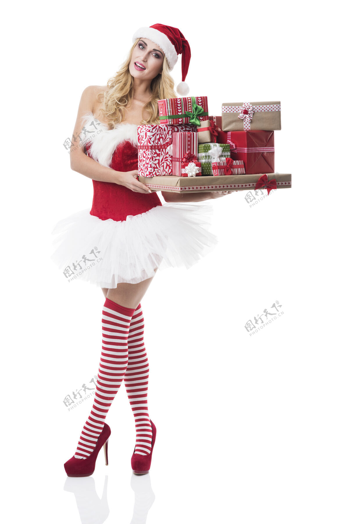 全长穿着圣诞老人服装的性感女人在白墙上摆姿势皮草迷人的女人圣诞礼物树
