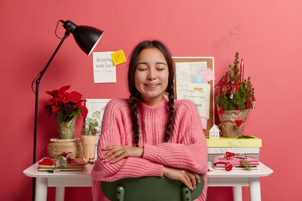 心情一个可爱的亚洲女孩 留着两条辫子 坐在椅子上闭着眼睛 想象着圣诞节发生了什么美妙的事情冬天装饰笔记本