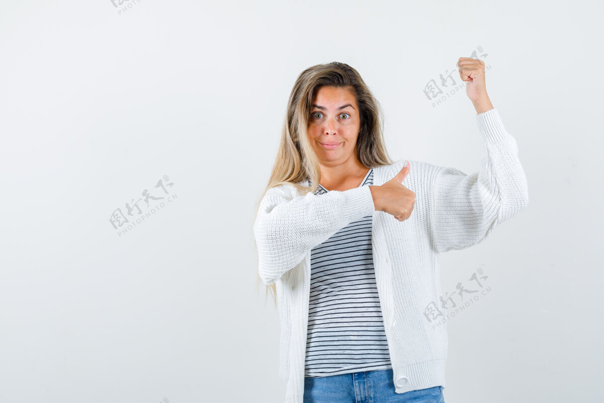 视图美丽女子的肖像展示获奖者的手势拇指向上在夹克衫 并期待愉快的前视图脸向上成人