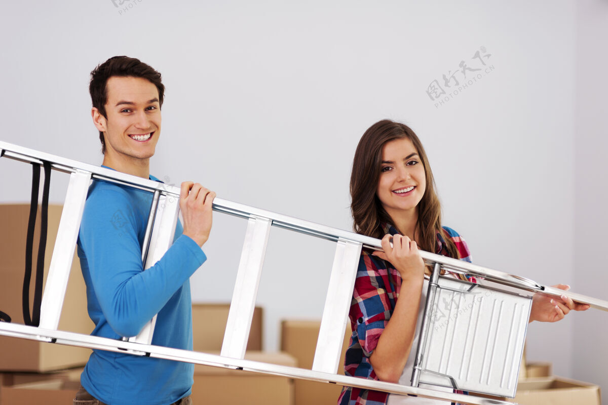 男人一对年轻幸福的夫妇在搬入新家时带着梯子搬家夫妻沉重
