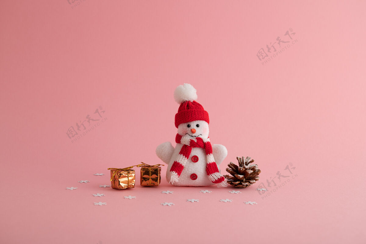 礼物特写一个有趣的雪人 小礼品盒 和一个粉红色背景的松果庆祝圣诞节玩具