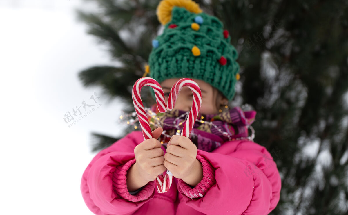 糖果快乐的孩子 在圣诞树下放着一根大糖果棒寒假概念女孩雪乐趣
