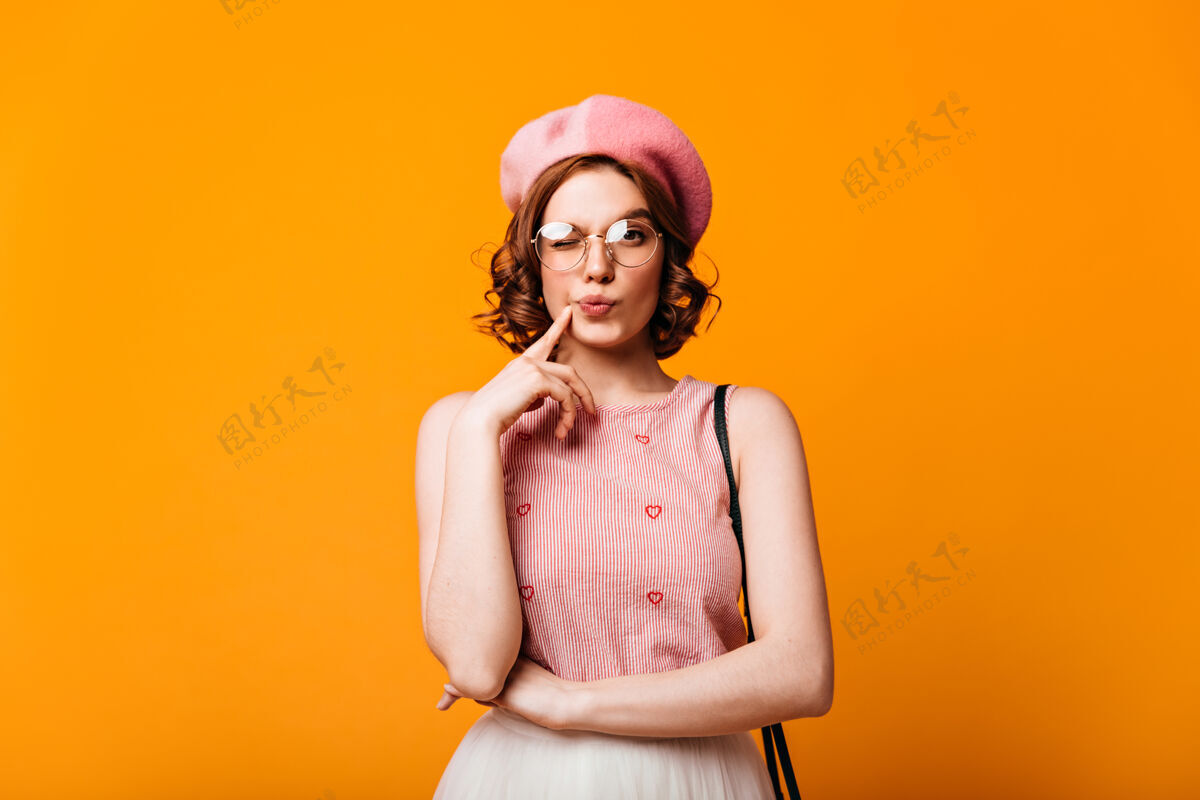 帽子戴贝雷帽的沉思优雅的女人的正面图黄色背景上站着的美丽法国女孩的摄影棚照片卷发女士一个