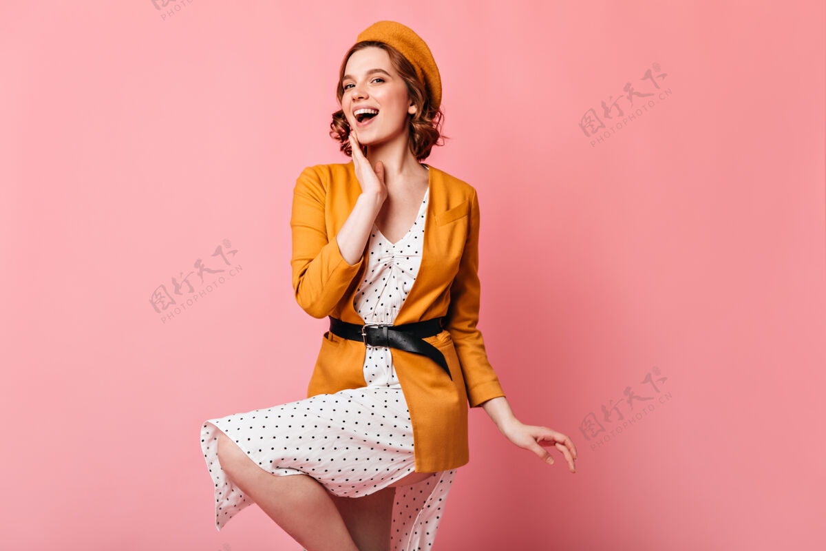手势优雅的法国女孩在粉红色的背景下跳舞摄影棚拍摄的灵感卷曲的黄色衣服的女人欢呼时尚卷发