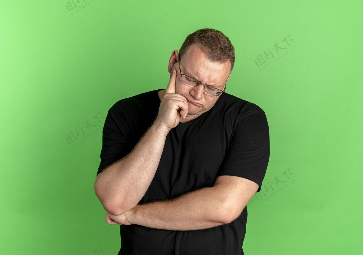 表情戴眼镜的超重男子身穿黑色t恤 脸上挂着沉思的表情 脸上露出绿色表情超重眼镜