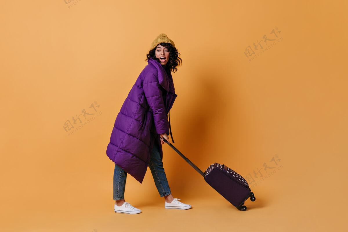 冬季装兴高采烈的年轻女子拿着手提箱摆姿势季节冬季女士
