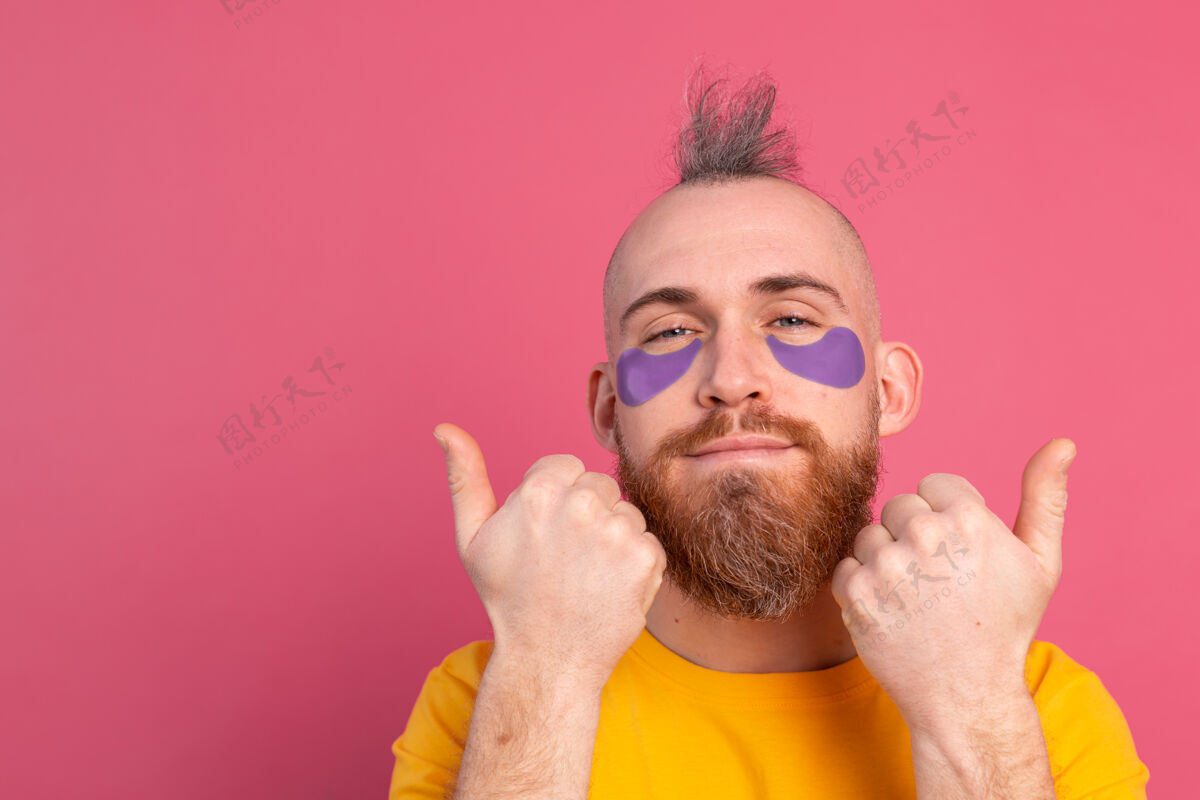 提升欧洲帅哥 留着胡子 穿着黄色t恤和紫色眼罩 戴着粉色眼罩治疗产品房子