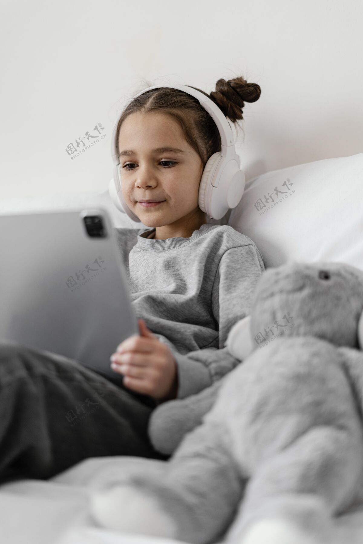 房子小女孩在床上用耳机用平板电脑科技室内设备
