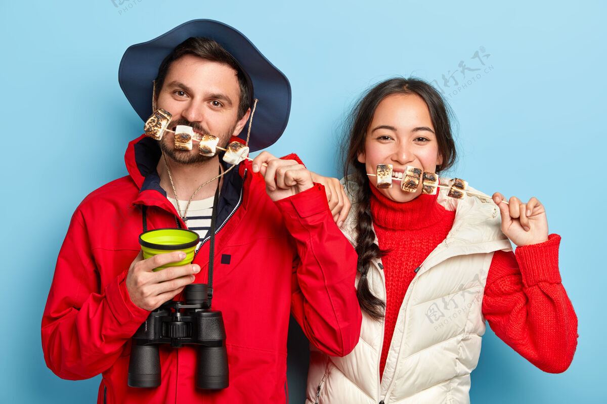 毛衣男女游客在篝火上吃着美味的烤棉花糖 在大自然中消遣 喜欢旅游和冒险 穿着休闲服棉花糖室内微笑