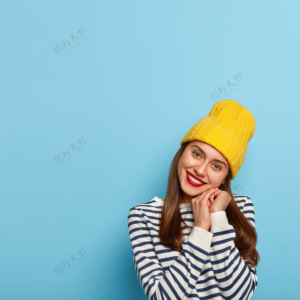 水手容貌开朗的女人仰着头 微笑温柔 双手合十 戴着黄色帽子和条纹水手套头衫黑发人季节