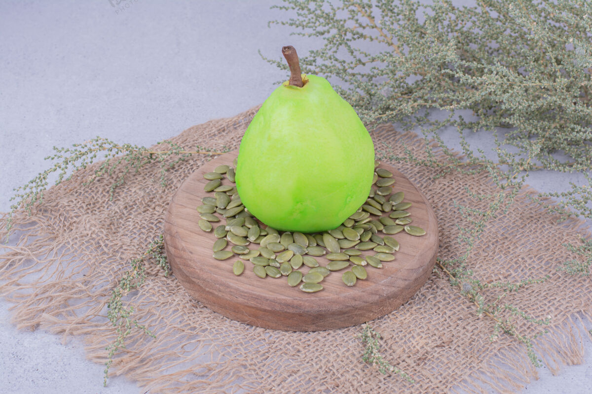 异国情调一个绿色的梨放在木板上 周围有南瓜子热带艺术酸味