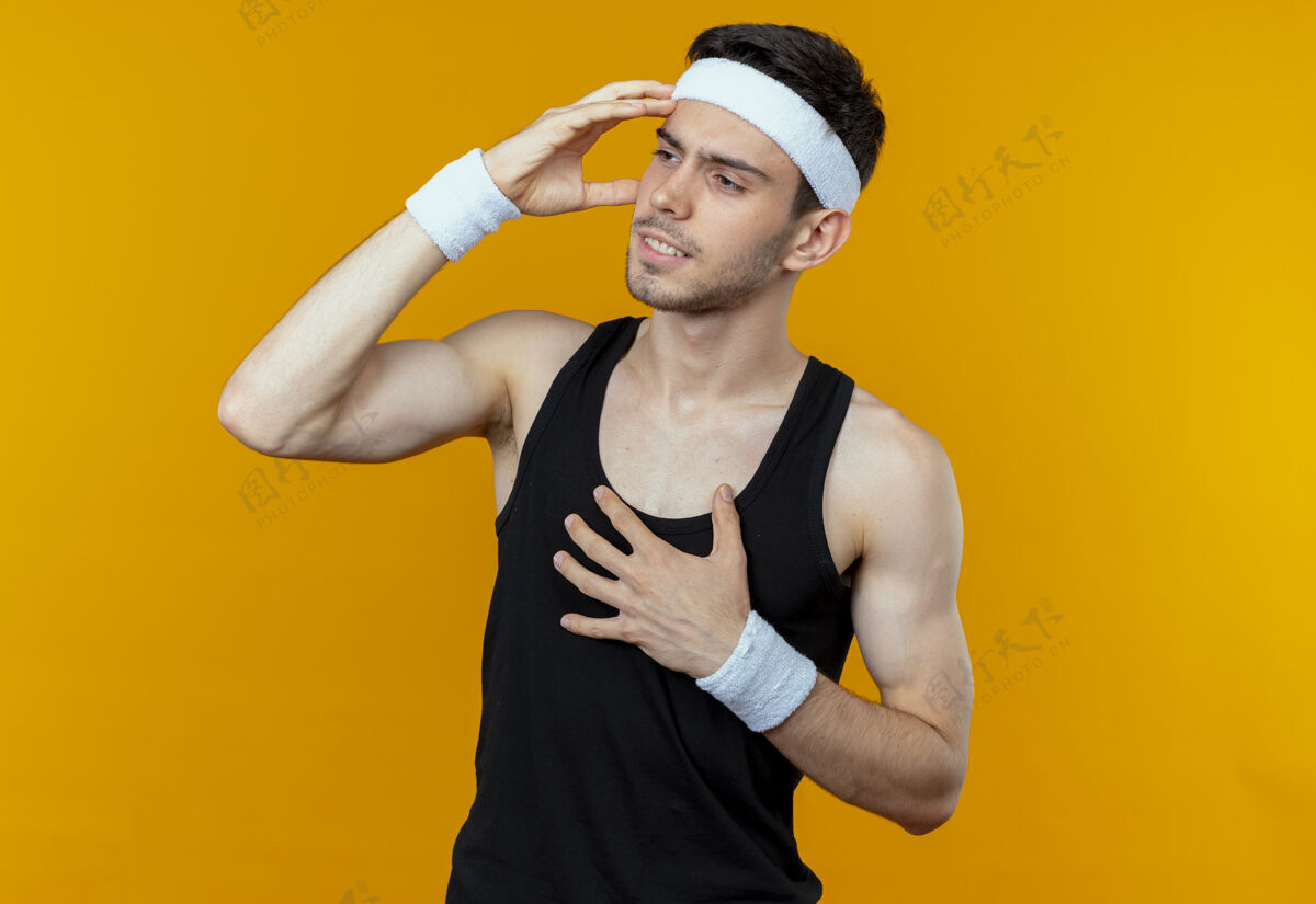看戴着头巾的年轻运动型男子 看上去很困惑 因为他把手放在头上 弄错了橙色手站年轻
