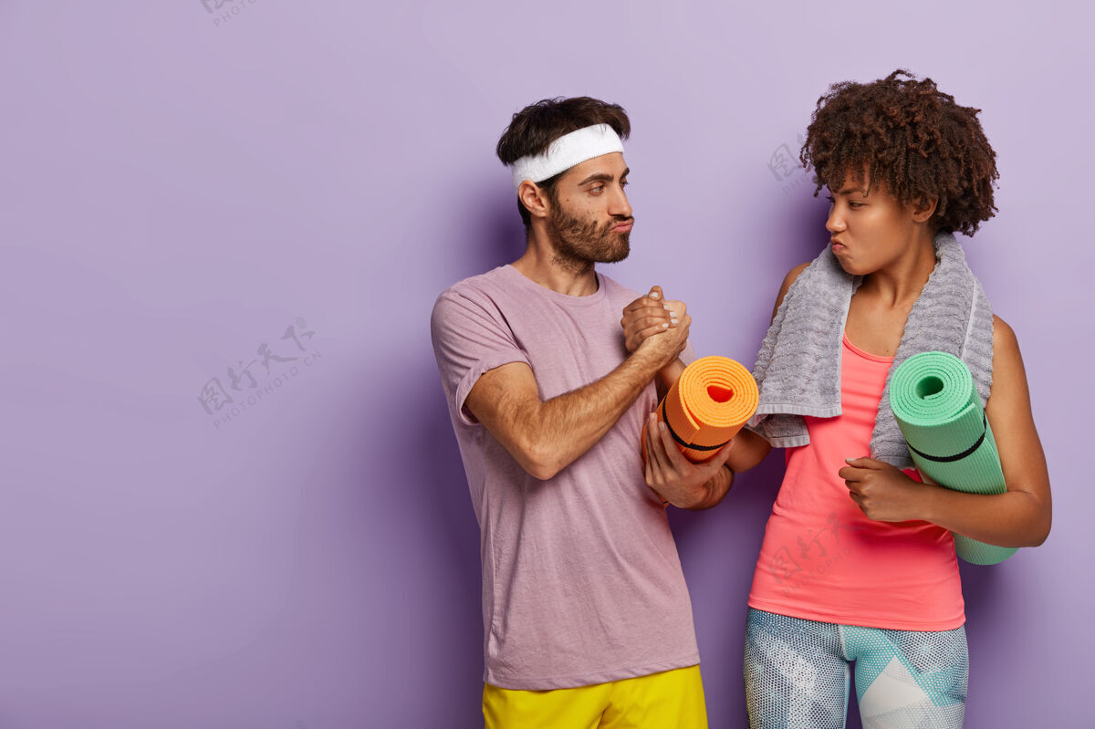 女性认真的男女混血儿手牵手 在健身房见面 一起训练 背健身垫动机运动装健康