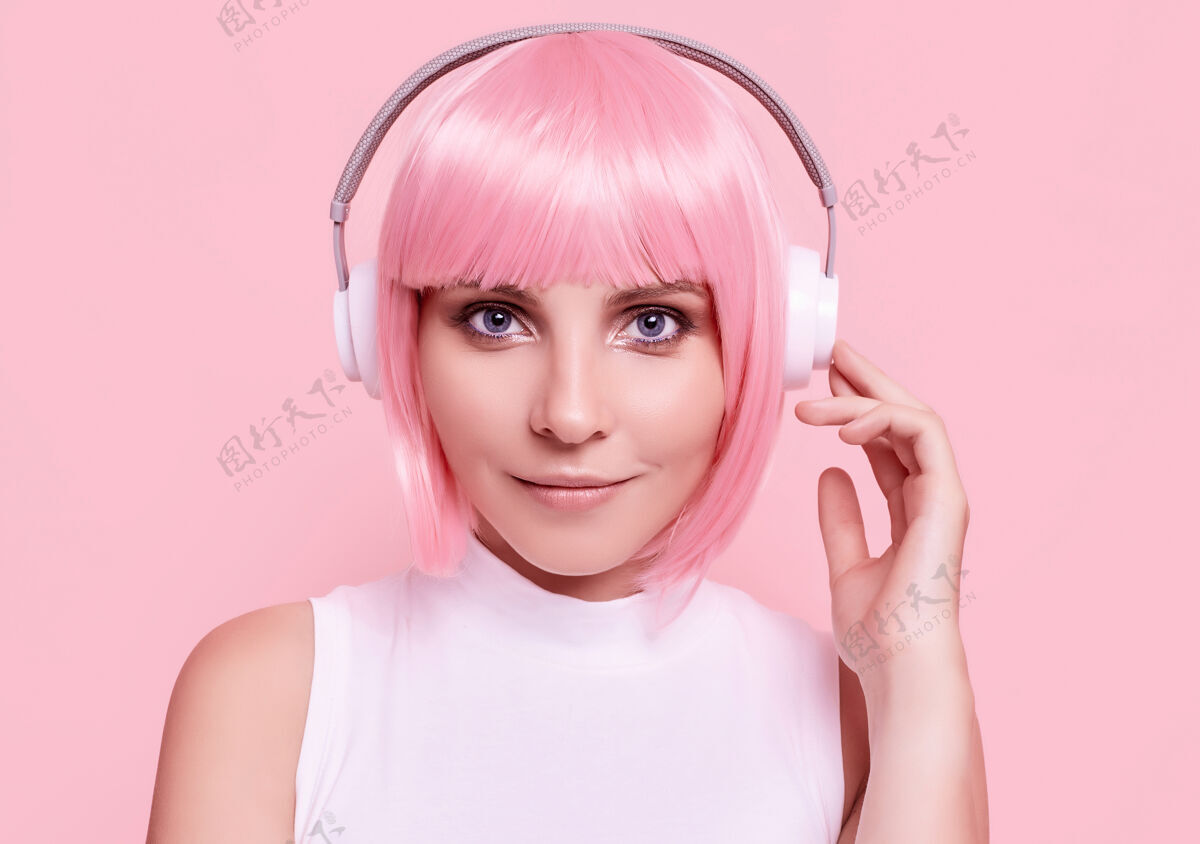假发粉红头发的美女肖像在耳机里欣赏音乐耳机音频发型