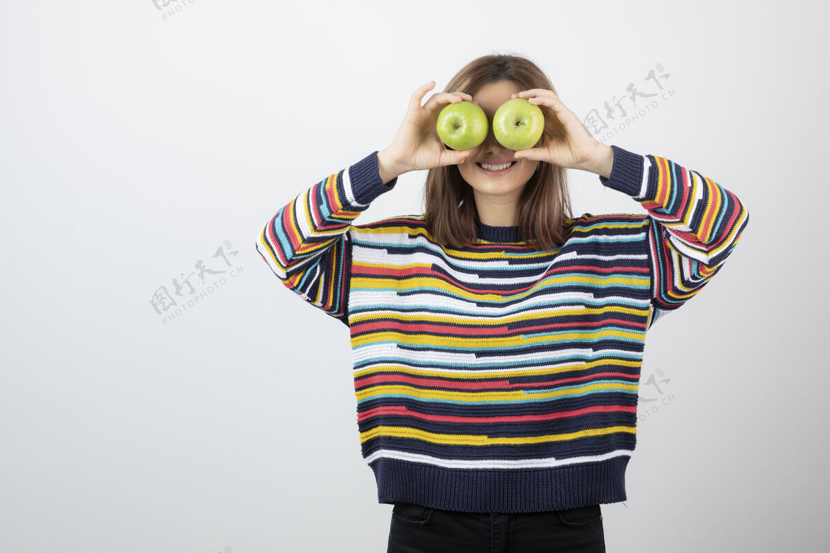 微笑一个穿着休闲装的年轻女人 眼前拿着青苹果水果姿势绿色