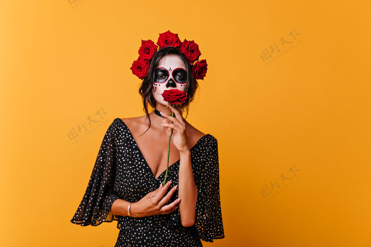 女巫穿着黑色礼服手持红玫瑰的浪漫死去的女孩室内女僵尸的画像戴着花环狂欢节化妆万圣节