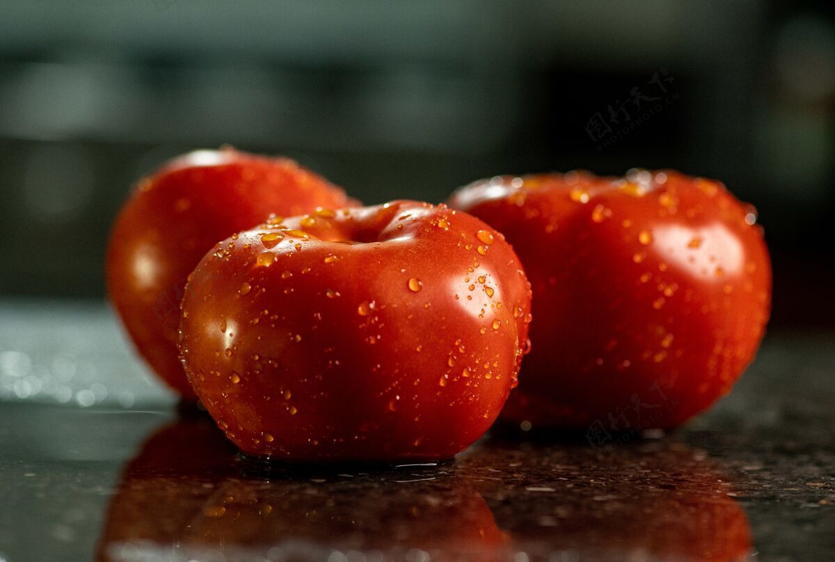 食物特写新鲜成熟的西红柿水滴在一个黑色花岗岩厨房台面摄影西红柿地中海