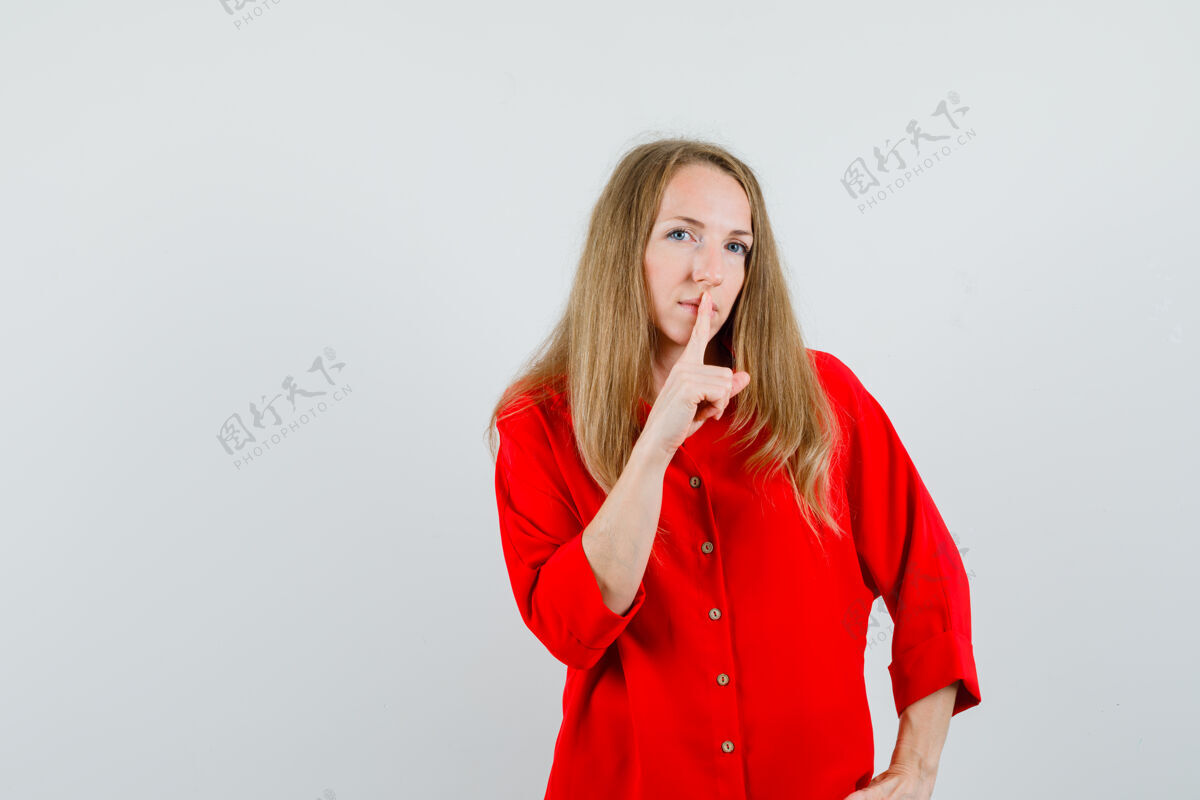 沉默一个穿着红衬衫的金发女人 表现出沉默的姿态 看上去很小心 魅力衬衫护理