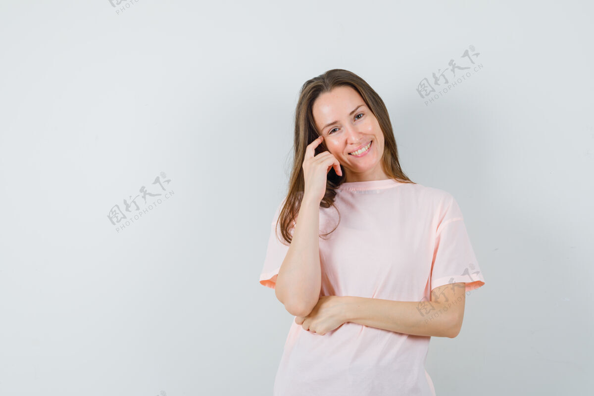 站立年轻女性穿着粉色t恤站在思考的姿势 看起来很愉快正面视图时尚民族思考