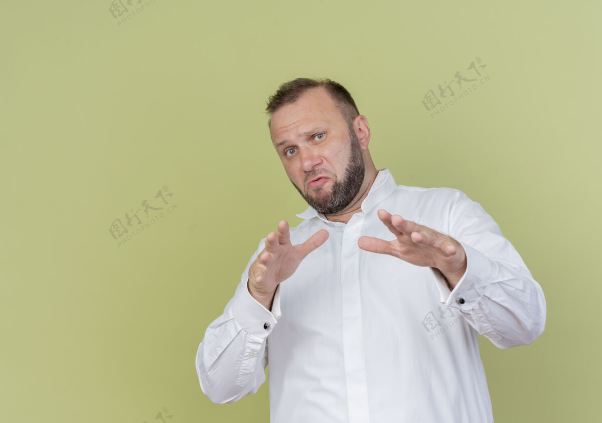 防御一个留着胡子的男人穿着白衬衫站在光墙上做着防卫的手势 伸出双手手势手握