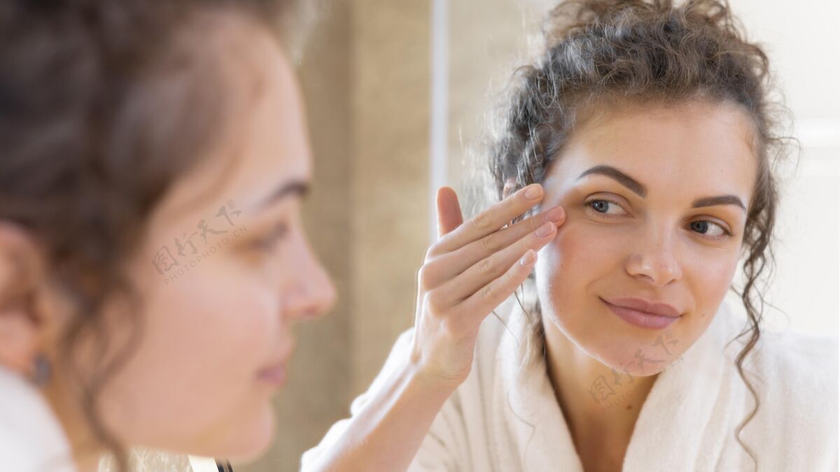 房子照镜子的时候在脸上涂面霜的女人面部护理镜子女人