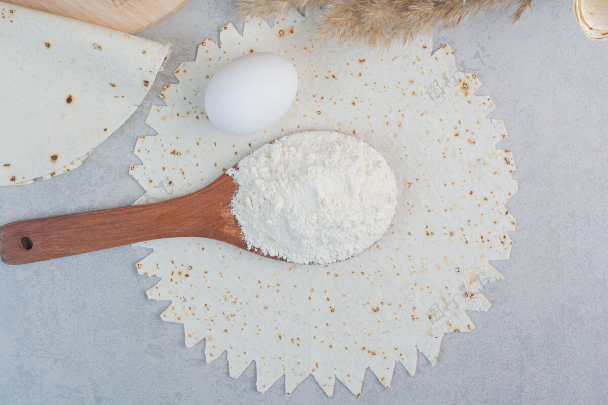 面包卷传统的拉瓦什 鸡蛋和面粉大理石背景高品质的照片面包汤匙面粉