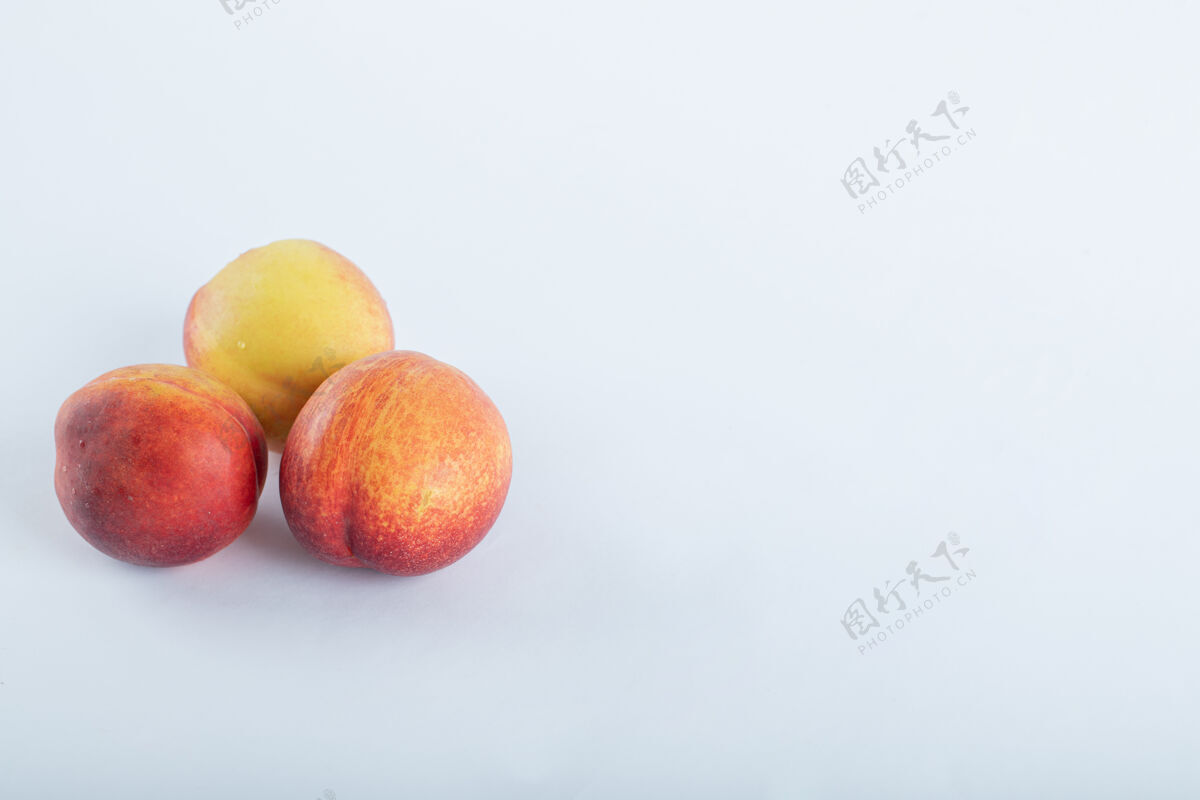 成熟三个新鲜的油桃在白色上天然桃水果