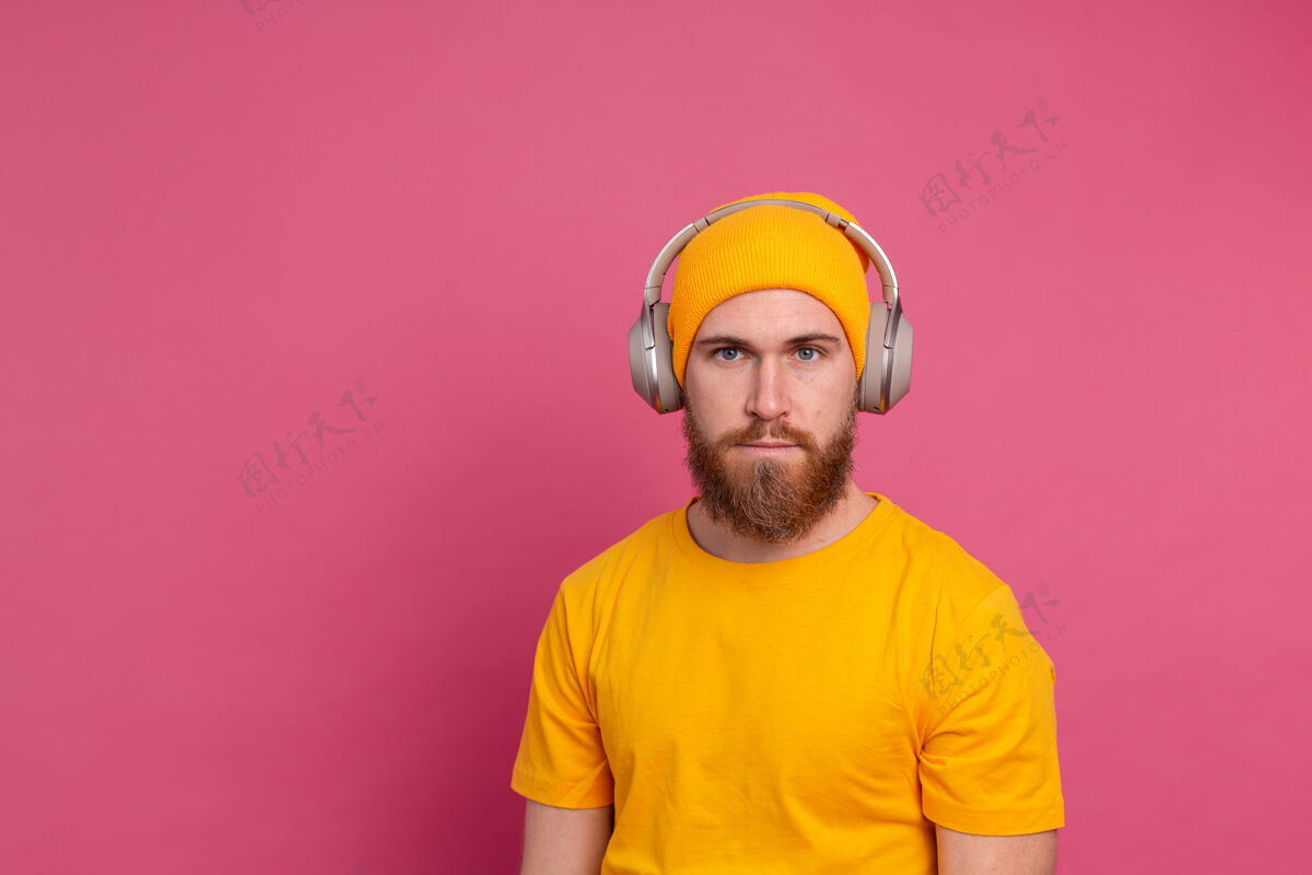 背景帅哥在随意地听着音乐 用耳机隔离在粉色背景上听力休闲休闲