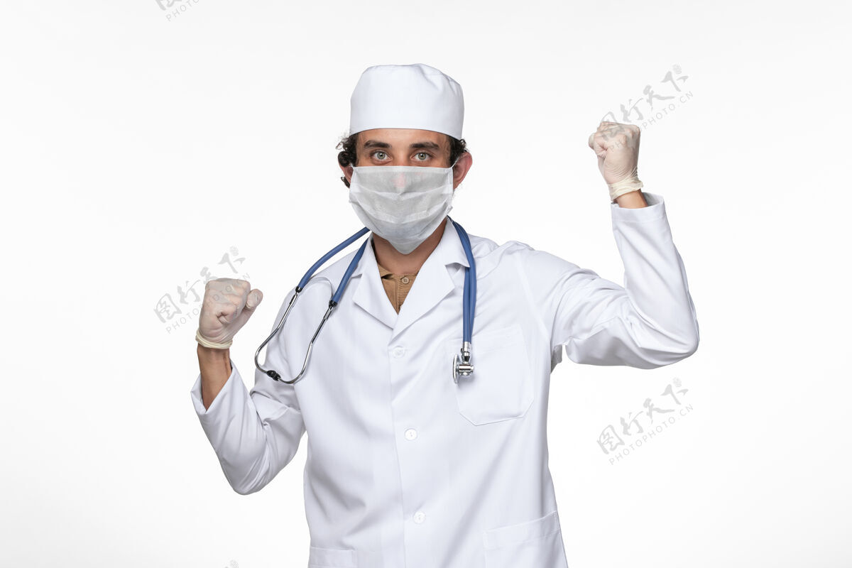 大流行正面图穿着医疗服的男医生戴着无菌口罩 以防白墙上的病毒传染专业人员听诊器疾病