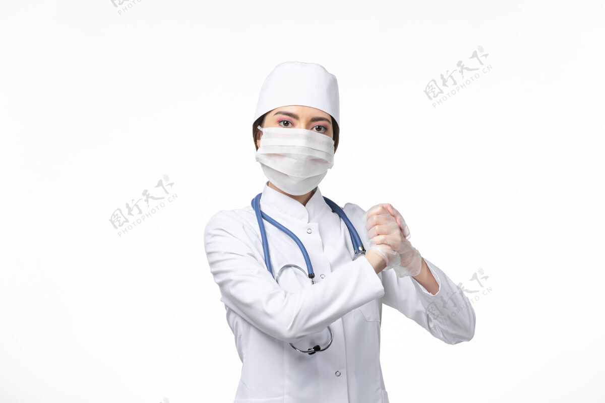 病毒正面图：女医生穿着白色无菌医疗服 戴着口罩 因为柯维德-在白色办公桌上摆姿势-柯维德病毒-大流行性疾病冠状病毒预防冠状病毒防护制服