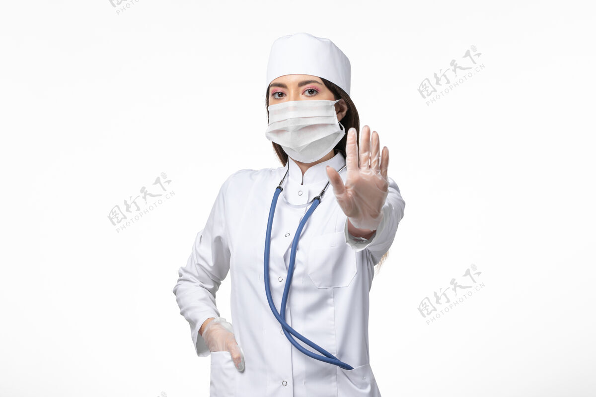 女性正面图：女医生穿着白色无菌医疗服 带着口罩 因柯维德-白桌子上的疾病柯维德-大流行病毒疾病冠状病毒疾病办公桌