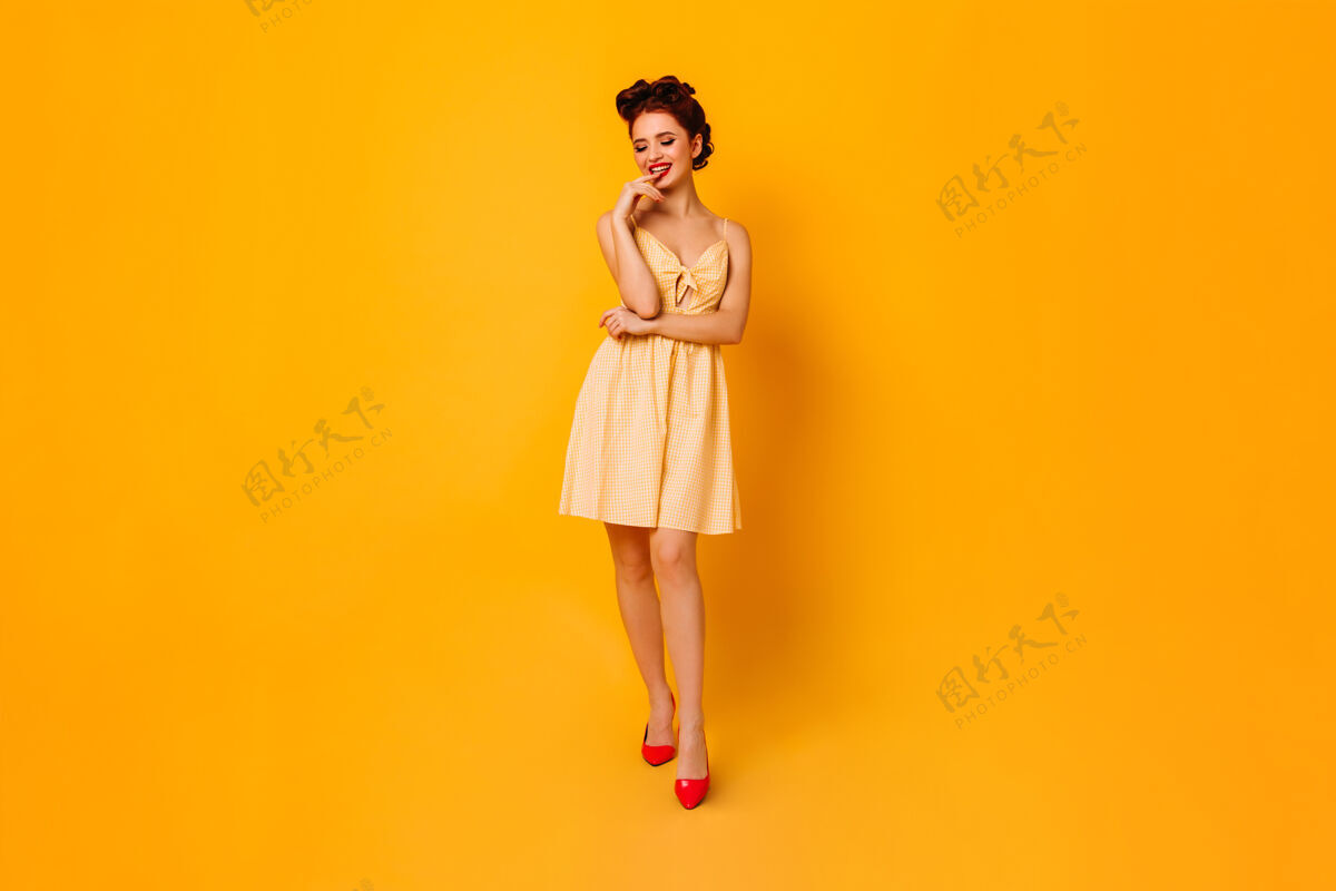 复古受启发的女人在黄色空间摆出俏皮的姿势穿着短裙的漂亮女士正在享受拍照大笑姜年轻人
