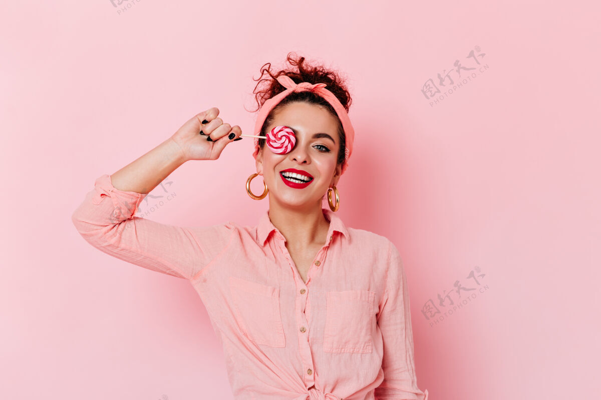 五十岁积极的女孩与红色唇膏在粉红色的装备和金耳环举行棒棒糖爱DIVA复古