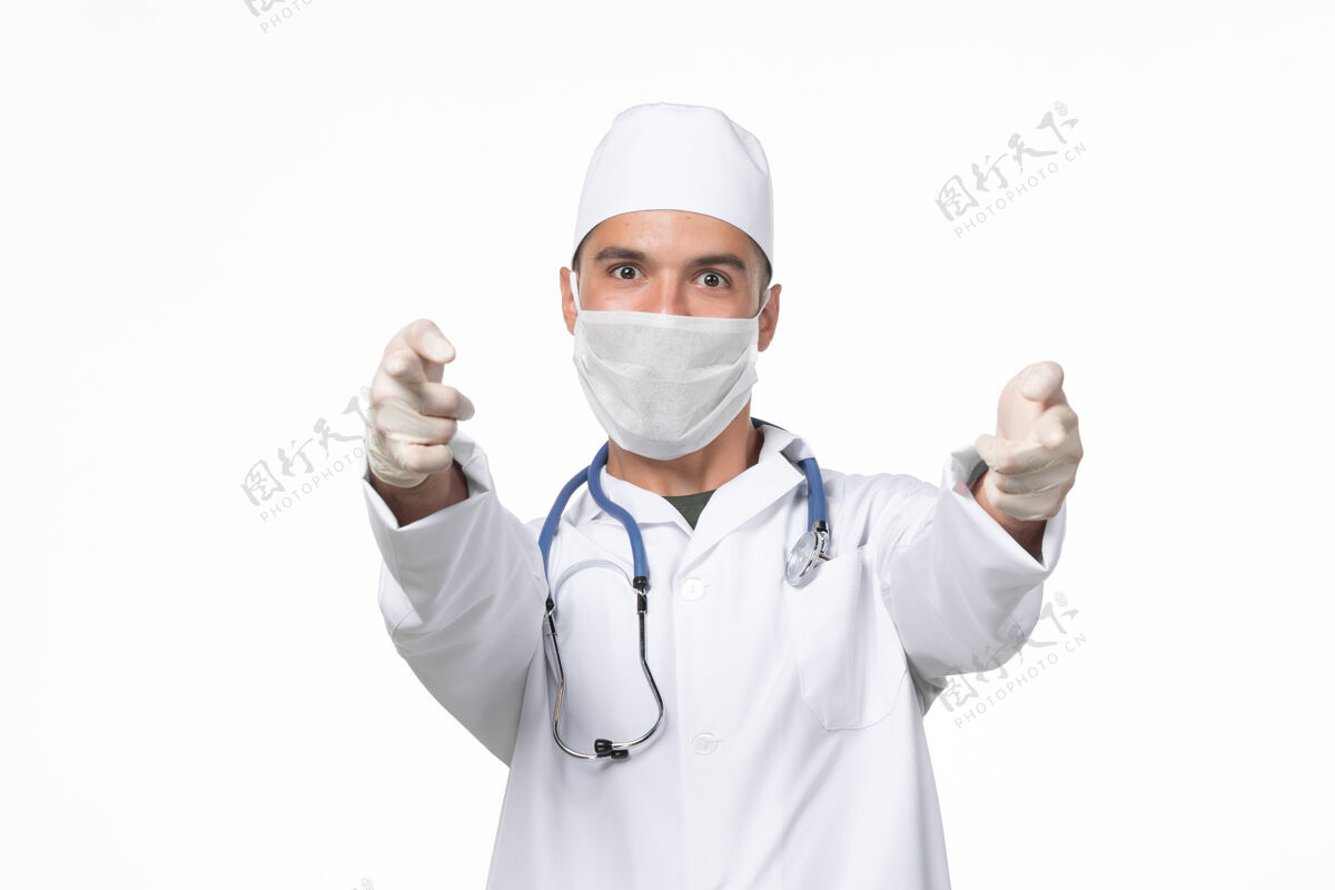 疾病正面图男医生穿着医疗服 戴着口罩 由于白墙上有病毒 病毒药大流行疾病男人病毒冠状病毒预防