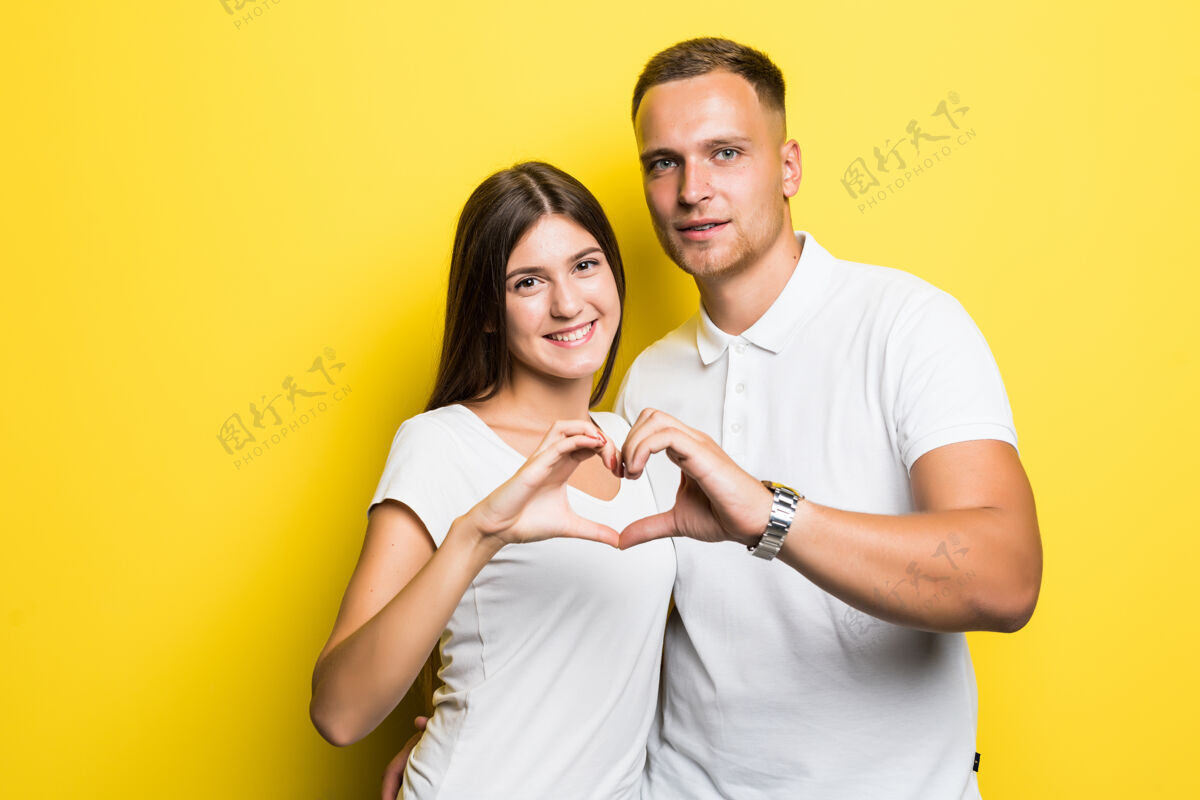 肖像阳光明媚的年轻夫妇身穿白色t恤 双手孤立 显示心迹休闲漂亮生活