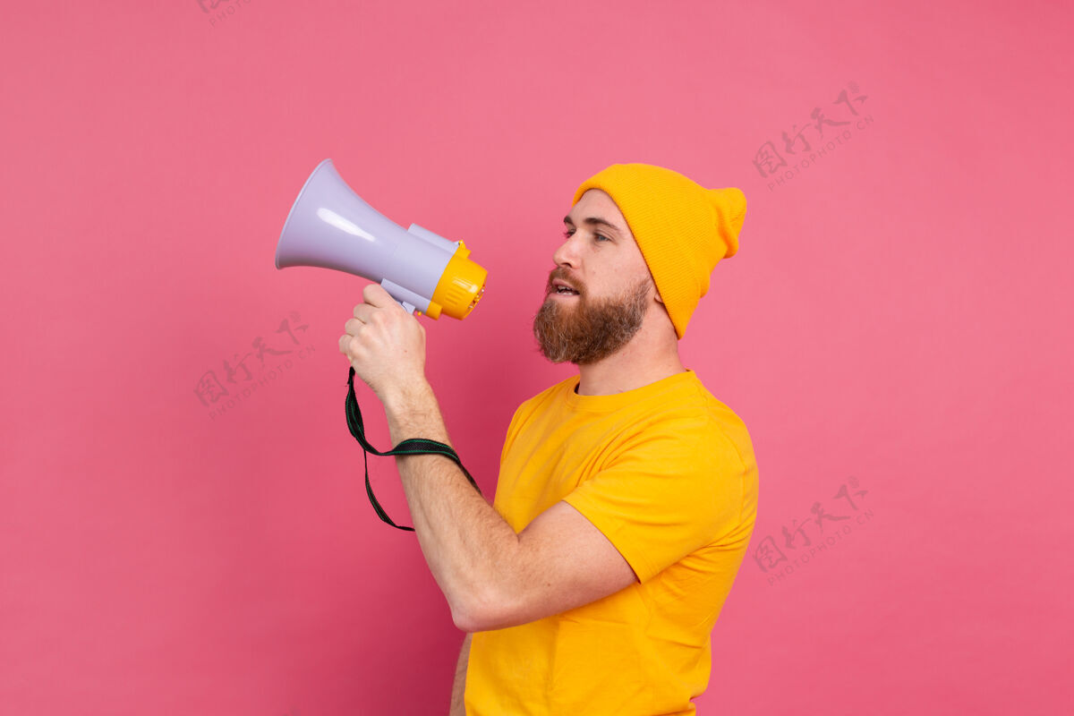 讲话注意 在粉红色背景下用扩音器喊叫的欧洲男人销售姿势注意