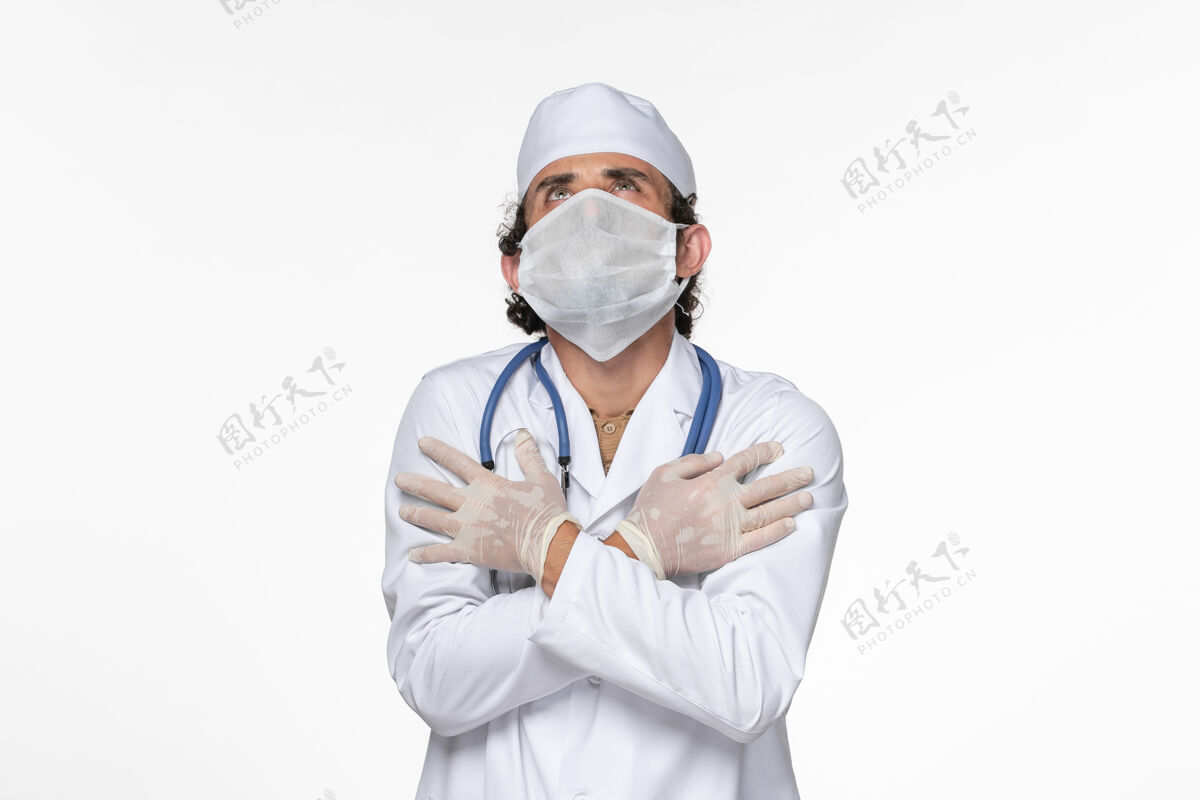 正面正面图：男医生穿着医疗服 戴着无菌口罩 以防白色办公桌上的冠状病毒引起大流行性疾病绝育男人护目镜