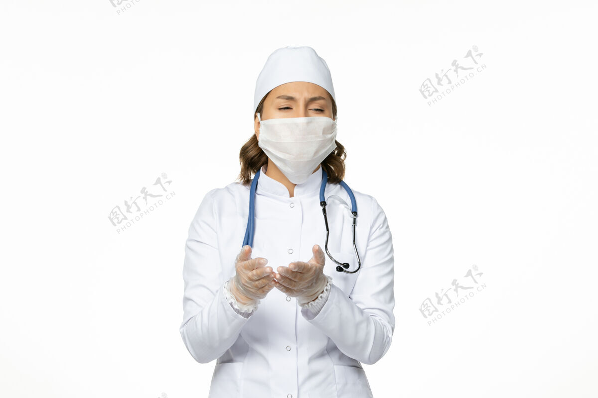 冠状病毒前视图女医生穿着白色医疗服 戴着口罩 由于白色地板上有冠状病毒病大流行病毒大流行人员疾病