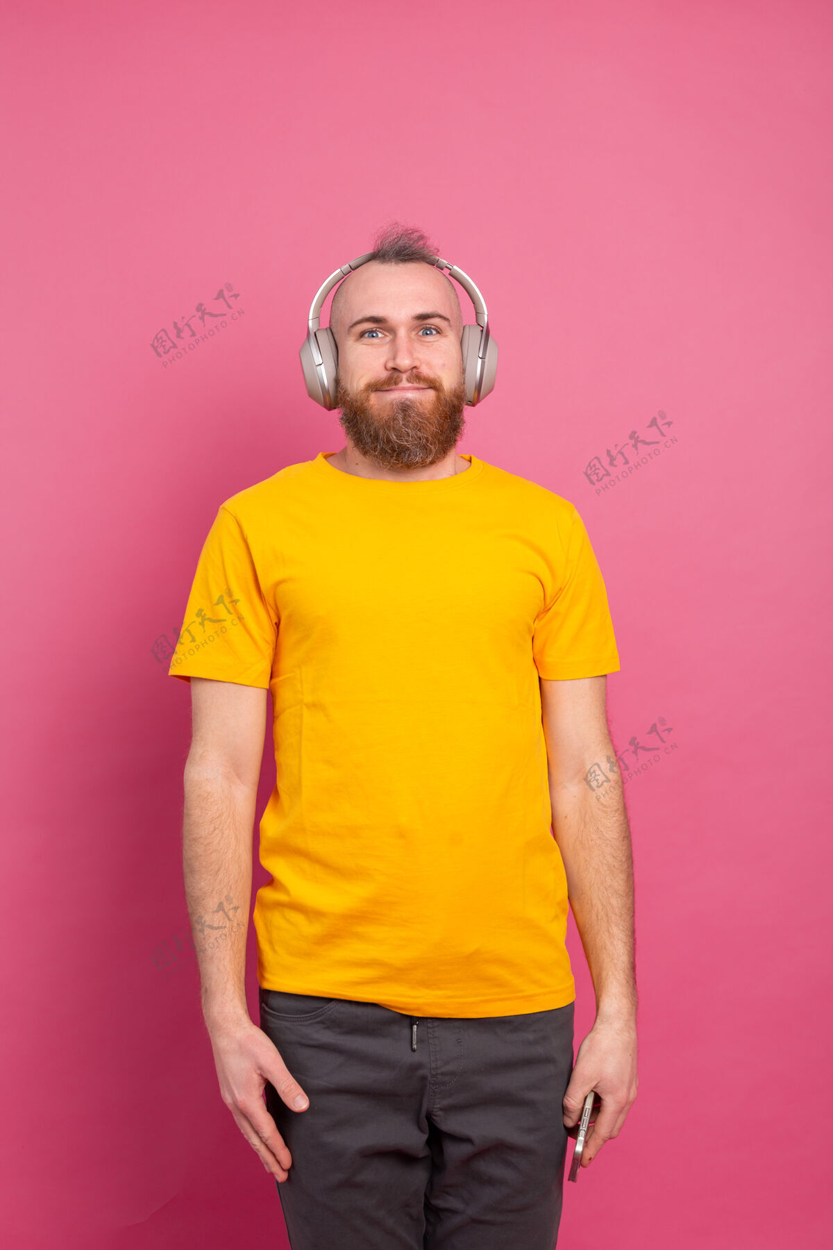 娱乐帅哥在随意地听着音乐 用耳机隔离在粉色背景上模型享受歌曲
