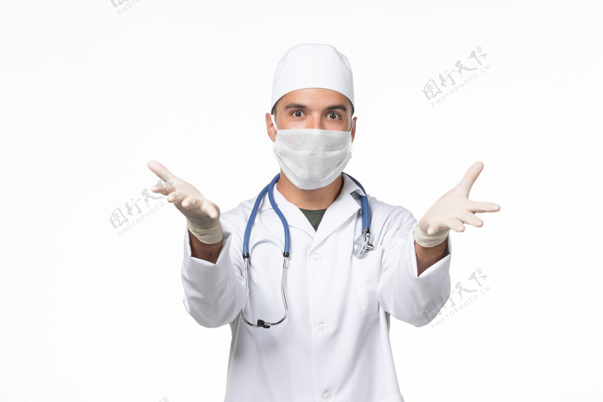 冠状病毒防护正面图：男医生穿着医疗服 戴着防病毒口罩-白色办公桌上的病毒药物-大流行性疾病医疗大流行听诊器