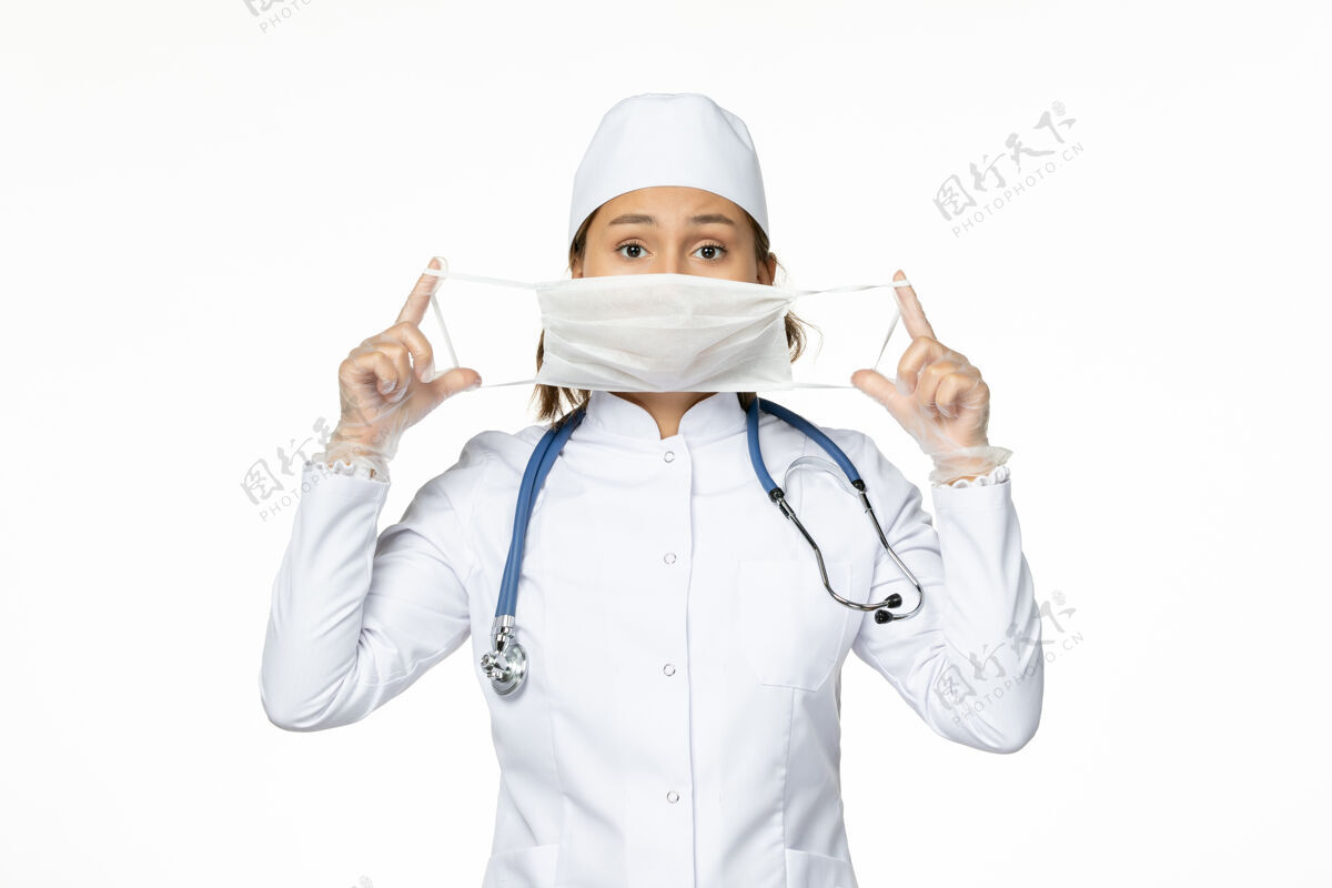 前线正面图女医生穿着白色医疗服 戴着无菌口罩 在白墙上隔离大流行性疾病的药物病毒医务人员大流行套装