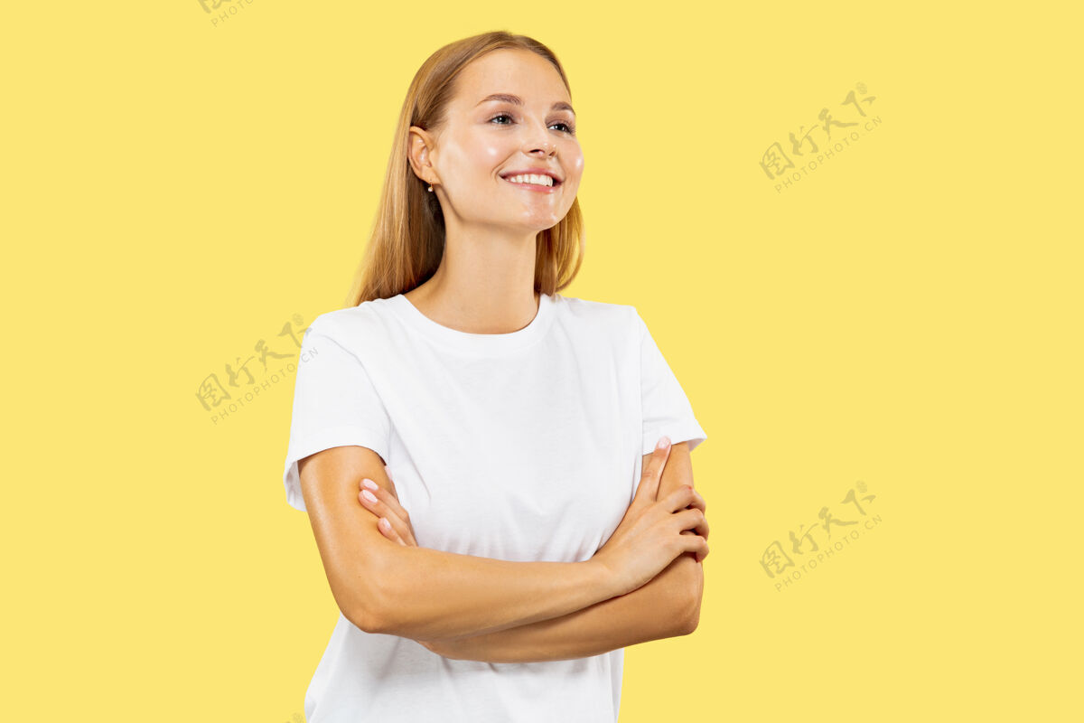 长度黄色工作室背景上的白人年轻女子半身像穿着白衬衫的漂亮女模特专业金发面部