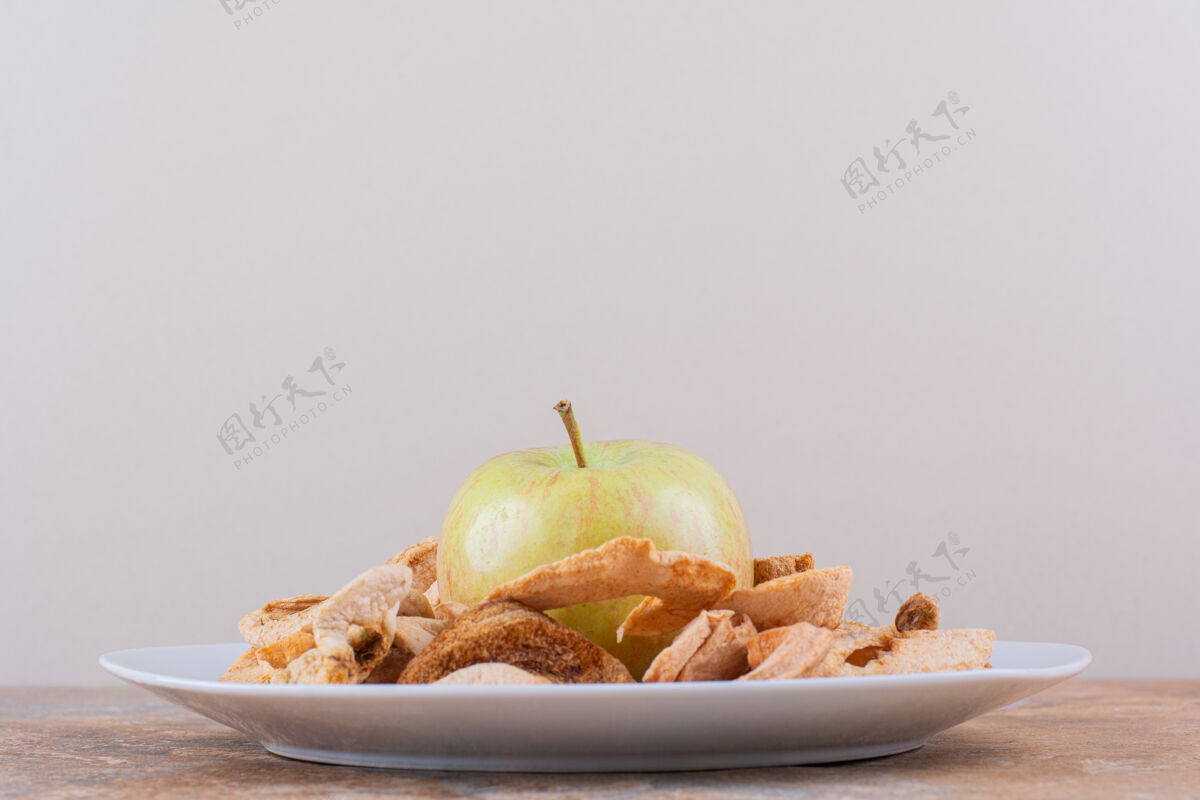 好吃白色的干苹果戒指和新鲜的绿色苹果放在大理石桌上高品质的照片小吃食品苹果