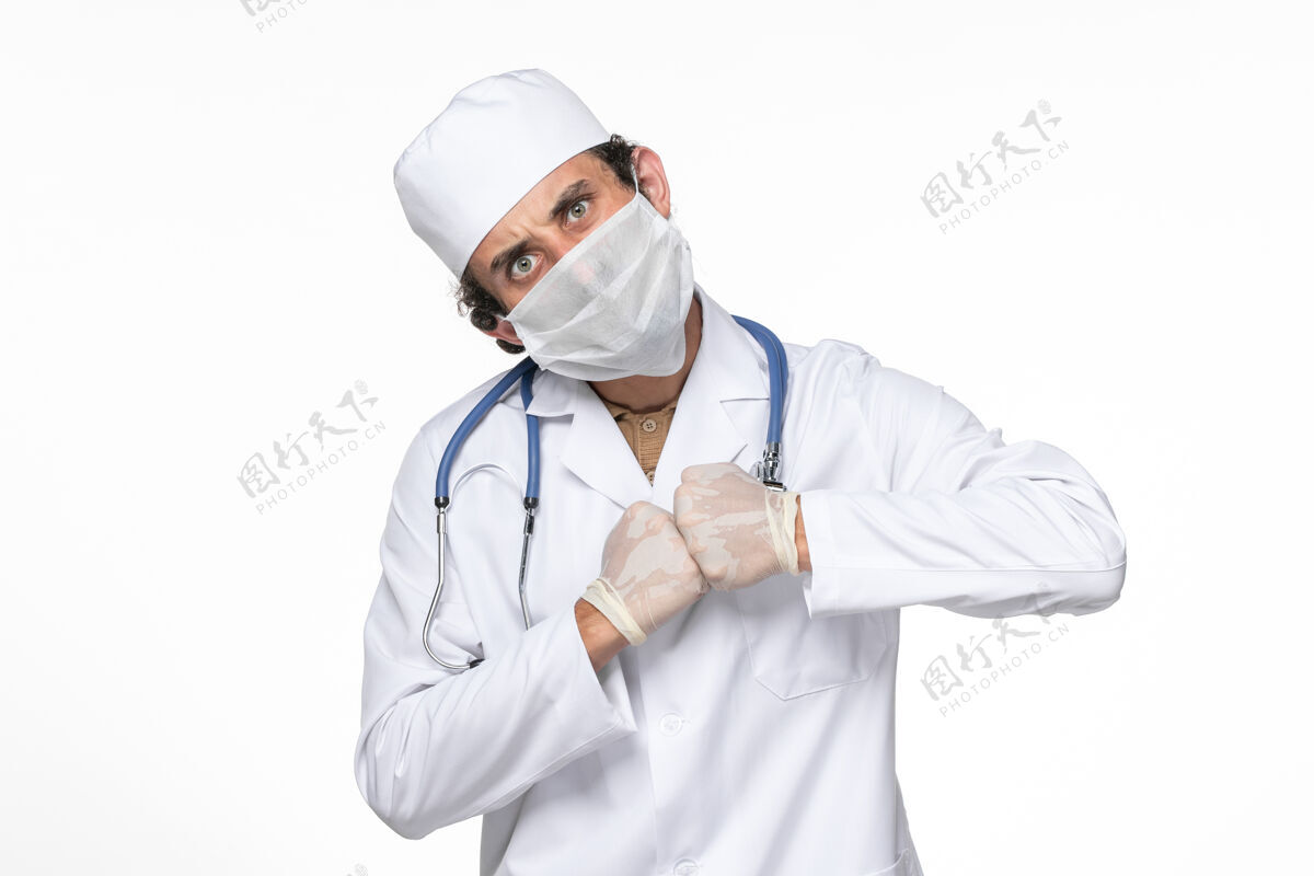 视图正面图：男医生穿着医疗服 戴着口罩 以防白墙病毒溅起冠状病毒大流行专业喷溅西装