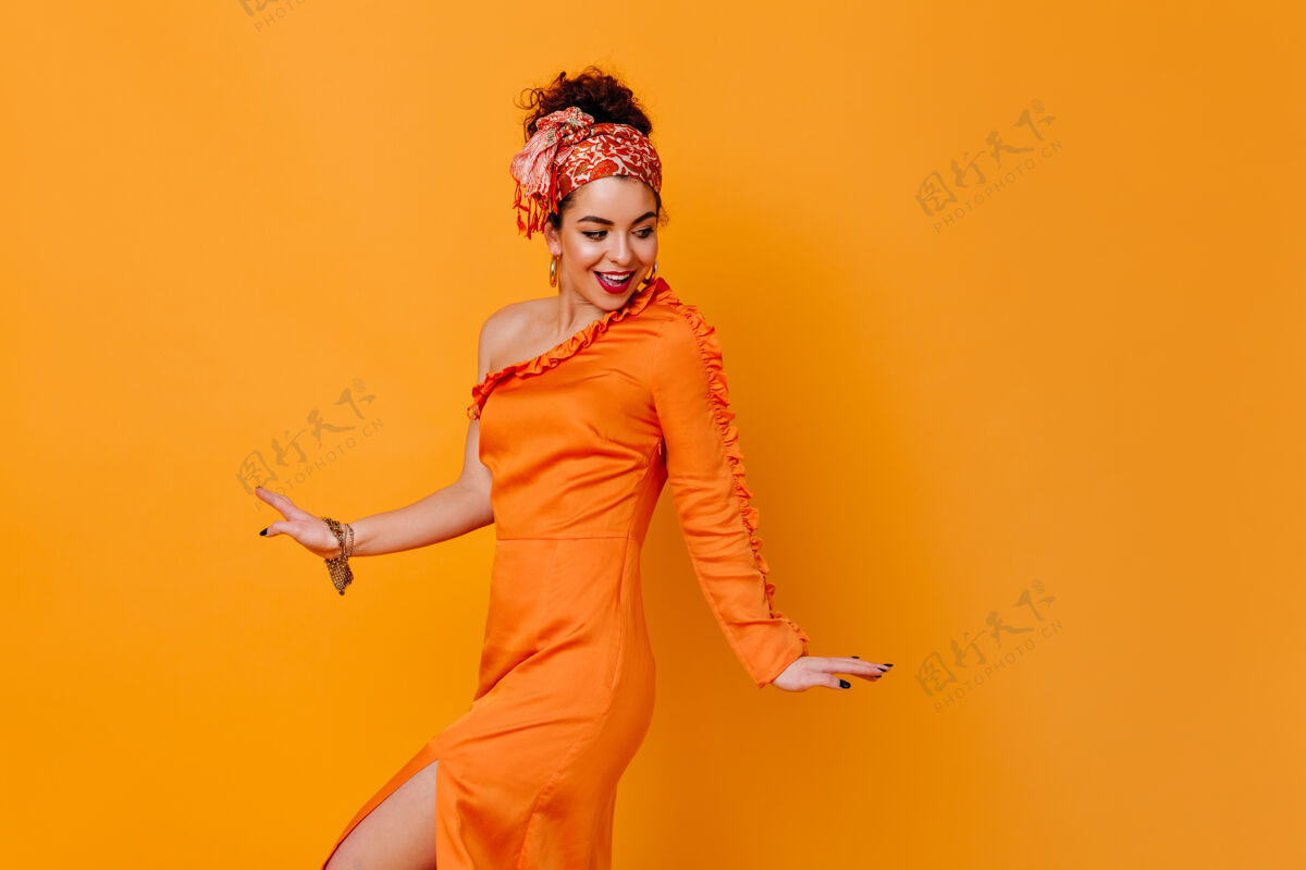 夏装优雅的女人在橙色的空间里露肩摆出风骚的姿势苗条手橙色连衣裙