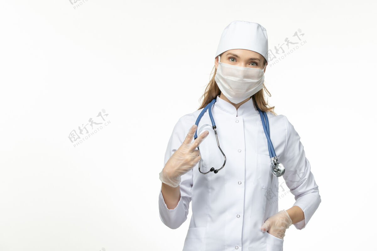 面罩正面图：穿着白色医疗服和面罩的女医生在白墙上防止冠状病毒感染正面冠状病毒疾病