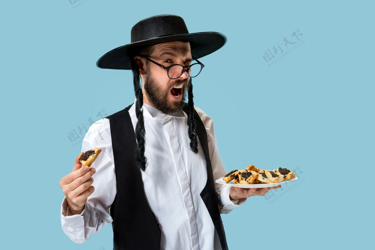 历史年轻的东正教犹太男子拿着哈曼塔森饼干庆祝普瑞姆节种子传统生活