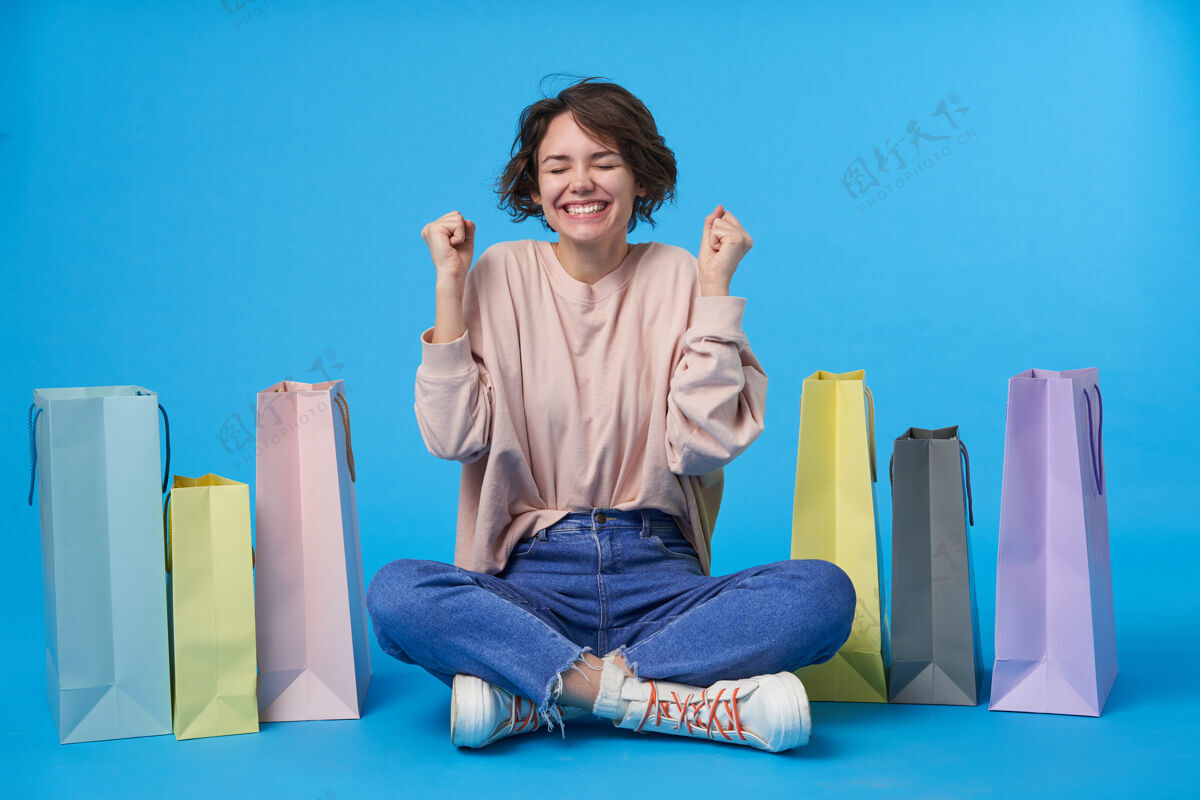 眼睛年轻迷人的黑发女人 短发 带着很多购物袋封闭女人购物狂